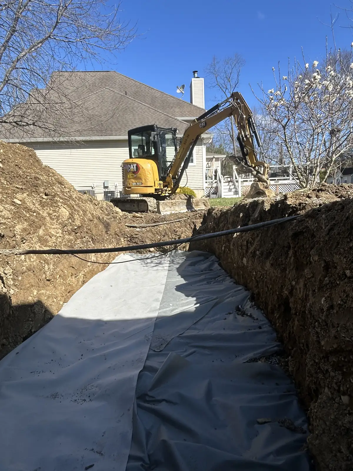 French drain trench being installed to solve water drainage issues