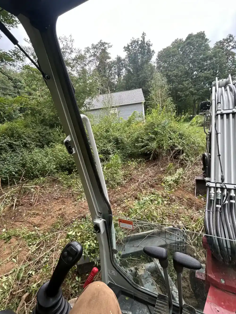 Excavator clearing brush and trees from a lot in Dutchess County
