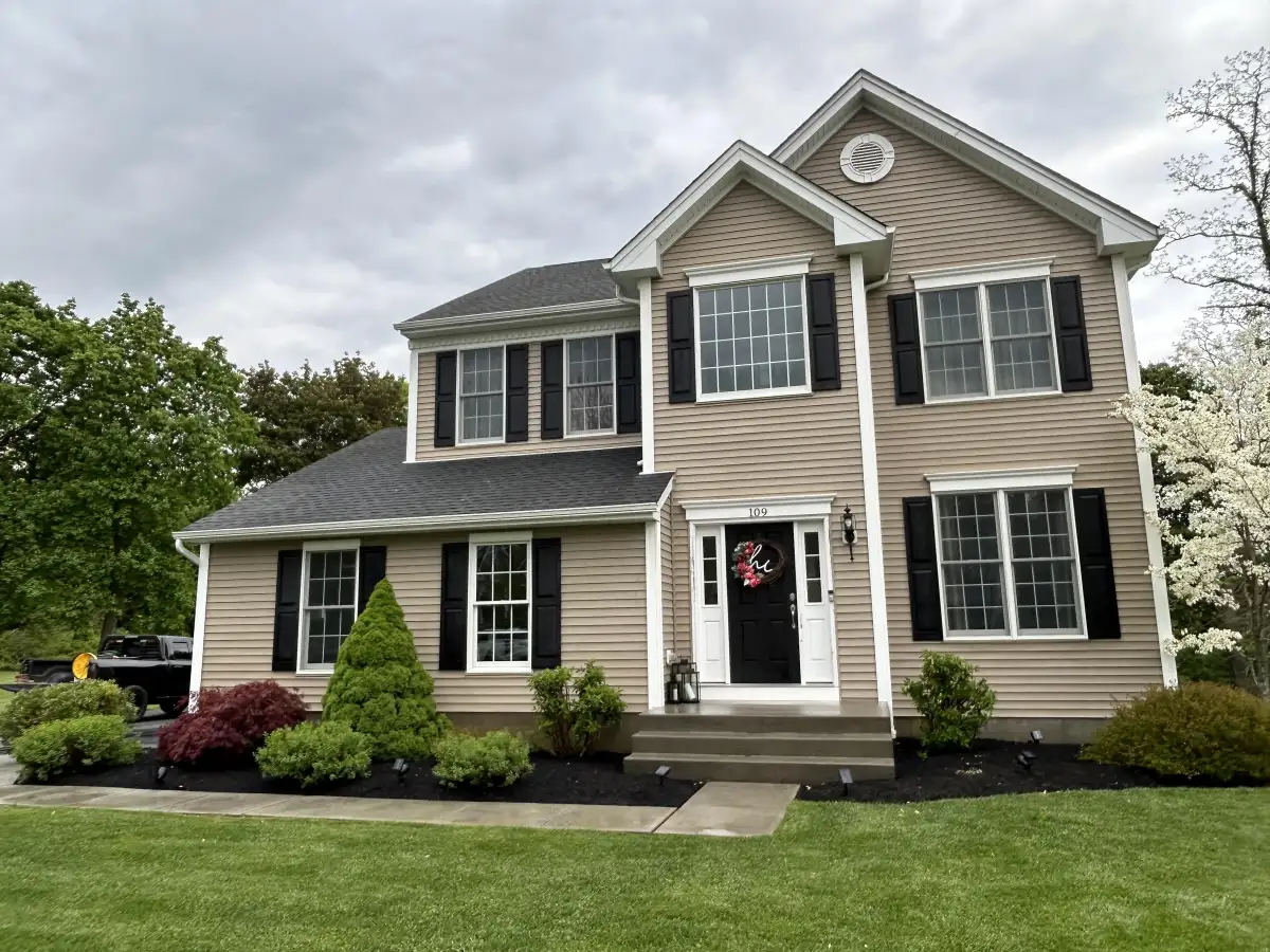 Clean house exterior with fresh landscaping after pressure washing in Dutchess County
